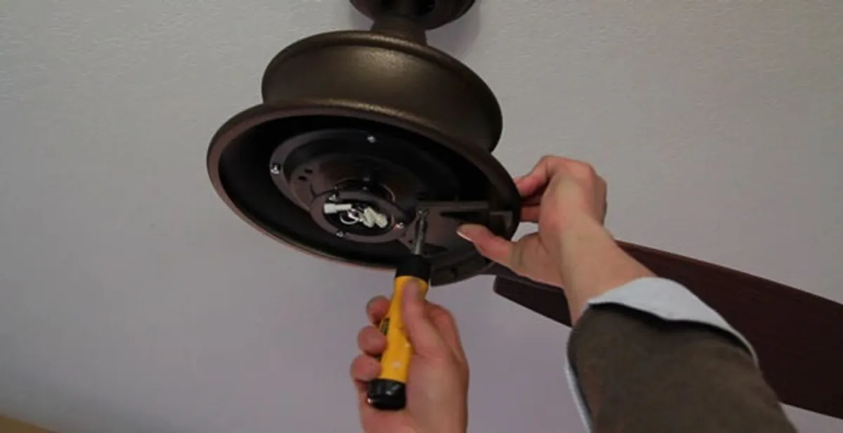 Electrician installing ceiling fan mounting bracket and fixture in Arlington, TX