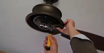 Electrician installing ceiling fan mounting bracket and fixture in Arlington, TX