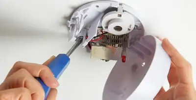 Certified technician wiring smoke detector during installation in Arlington, TX